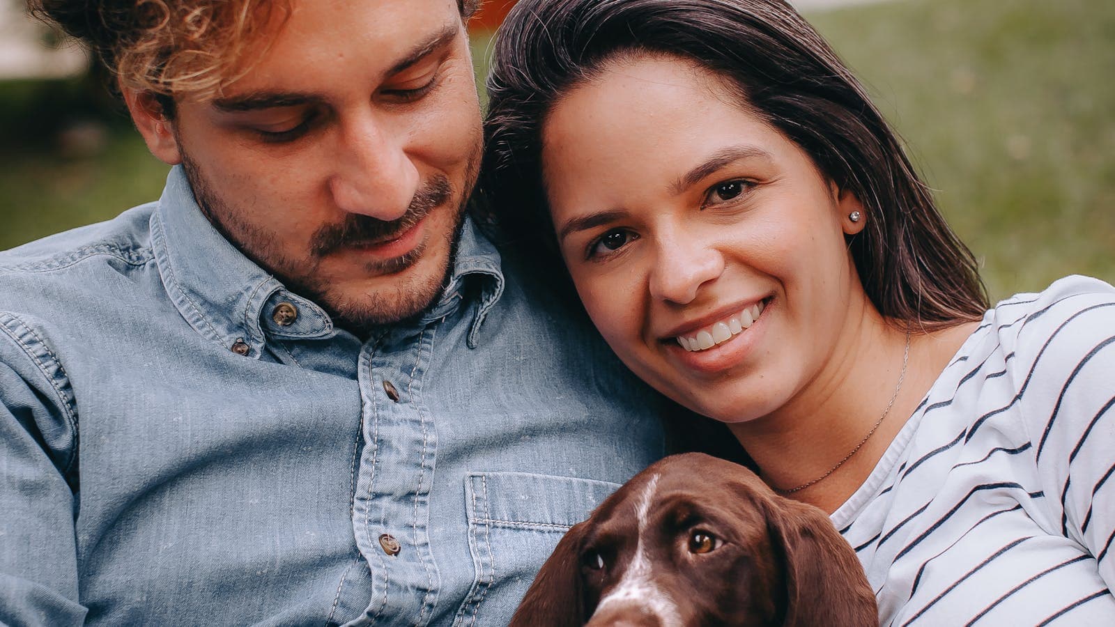 Smiling couple cuddling a new dog outdoors